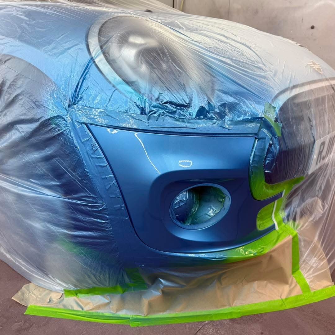 Blue front bumper masked during the respray process